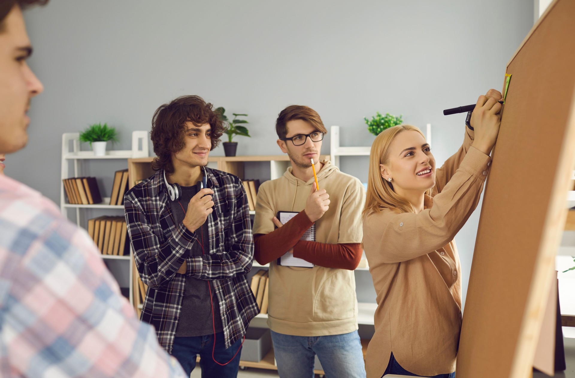 Teenager college student schoolmates brainstorming standing together at board